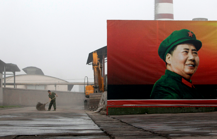 En arbeider koster gaten vedsiden av en plakat med formann Mao Zedong, ved et kraftverk i landsbyen Nanjie, utenfor Luohe i det sentrale Kina.									Foto: REUTERS/Jason Lee/Scanpix