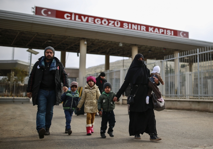 Syriske familiemedlemmer krysser grensen inn til Tyrikia ved grenseovergangen Civegozu, nær Hatay, sørvest i Tyrkia 17. desember. AP Photo/Emrah Gurel