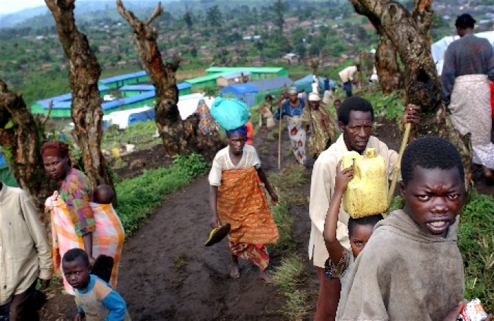 Over og jenta på nest eside: Nord-Kivu, Den demokratiske republikken Kongo, Afrika 20021110: I begynnelsen av september 2002 ble mange kongolesiske flytkninger fra to leirer i Rwanda tvunget tilbake over grensen til DR Kongo. I løpet av et par uker kom over 10.000 personer til den lille byen Kichanga (Nord Kivu). Fra myndighetenes side fikk de beskjed om å klare seg så best de kunne på egenhånd. FN ba Flyktningerådet om registreringering av de hjemvendte, samt distribusjon av "non food items" på vegne av UNHCR. Her noen av de hjemvendte flyktningene / innfødte i sin primitive landsby.																Foto: Heiko Junge / SCANPIX